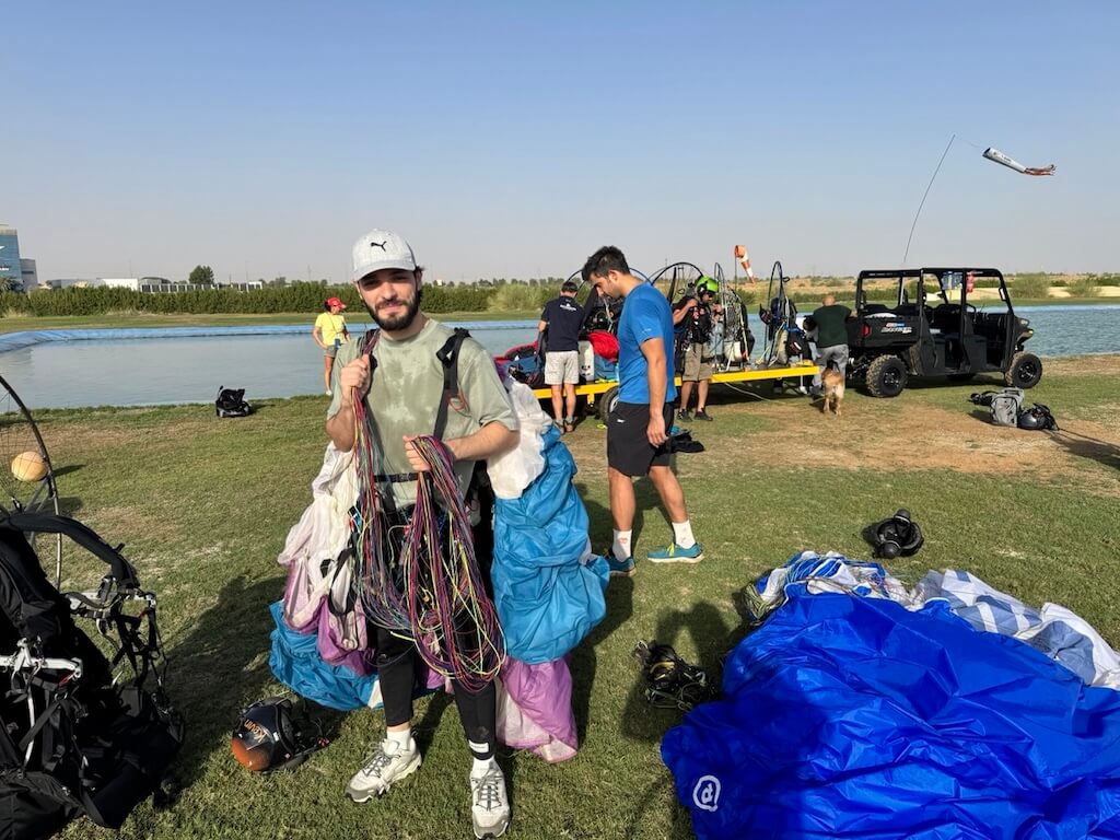 Me sweaty, wearing a harness, holding my wing like a trophy of exhaustion Salam Waddah wearing a harness, holding paramotor wing